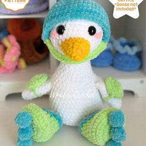 May include: A plush crochet goose toy with white body, teal hat, orange beak, and light green accents on the feet and wings. The image includes text stating CROCHET PATTERN, 8 Seasonal outfits! *Goose not included*, Wonder Crochet, and DIGITAL DOWNLOAD.