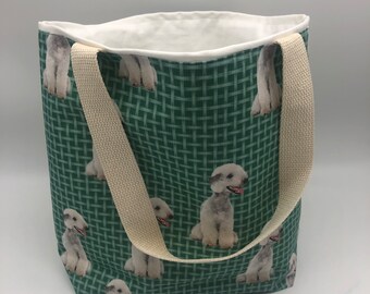 May include: A green tote bag with white straps and a repeating pattern of white dogs. The dogs are all facing the same direction and have their tongues sticking out.