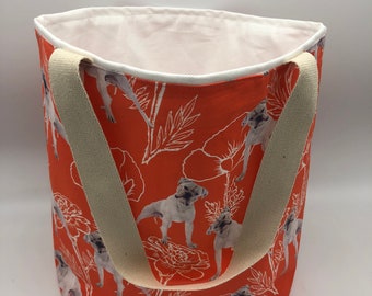 May include: Orange canvas tote bag with white floral and dog print. The bag has two cream-colored straps.