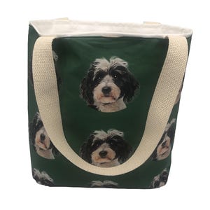 May include: A green canvas tote bag with white straps. The bag has a repeating pattern of a black and white dog's face.