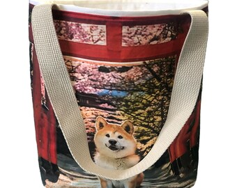 May include: A red and white tote bag with a Shiba Inu dog standing in front of a red Japanese gate. The bag has cream colored straps.