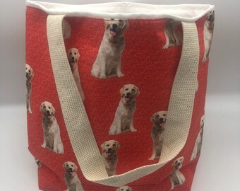 May include: A red canvas tote bag with white straps and a pattern of golden retriever dogs. The dogs are all sitting and looking at the camera.