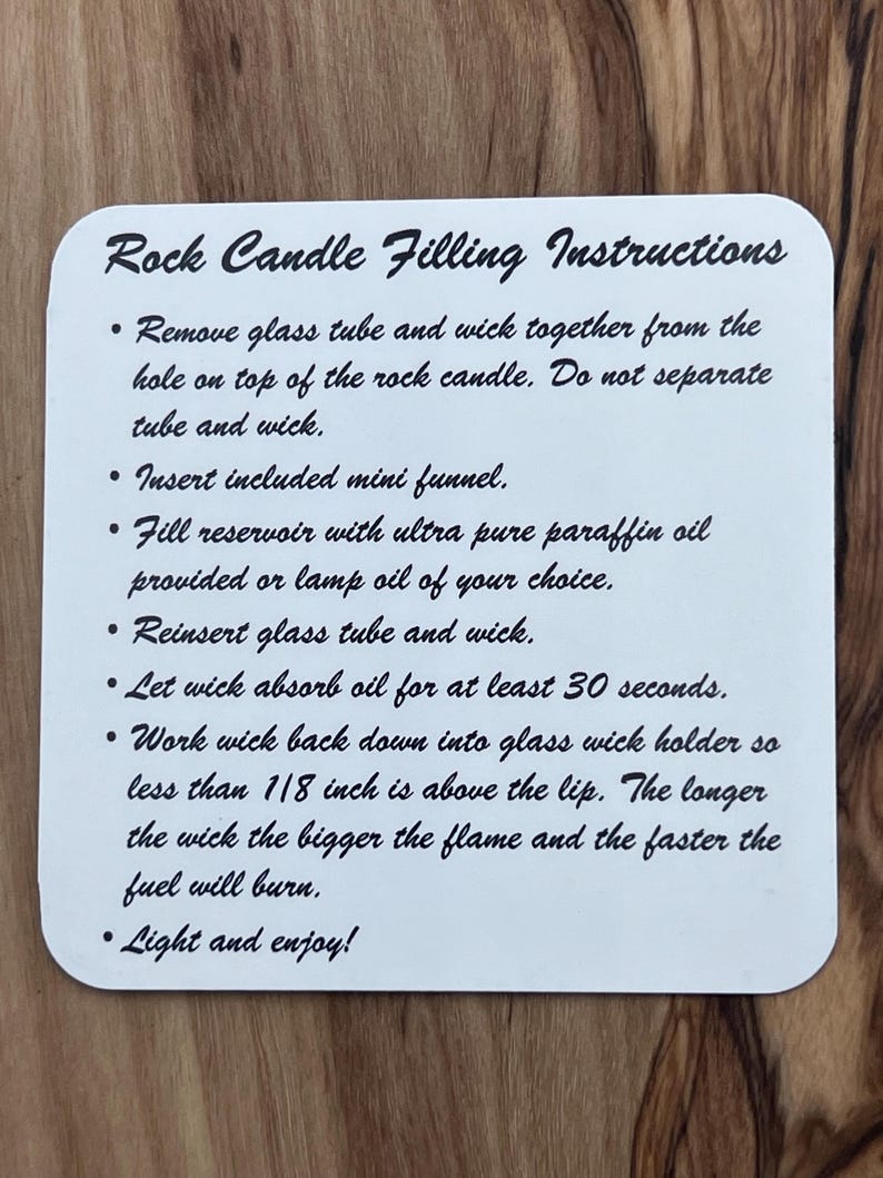 May include: White card with black text outlining instructions for filling a rock candle. The instructions include removing the glass tube and wick, inserting a funnel, filling the reservoir with paraffin oil, reinserting the tube and wick, letting the wick absorb oil for 30 seconds, working the wick down into the holder, and lighting the candle.