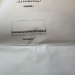 May include: A black and white illustration of two diagrams labeled "Diagram J" and "Diagram K". Diagram J depicts a series of connected rectangles. Diagram K shows a rectangle with a fringe along the bottom edge. The text "DOLL IN GREEN COAT" is at the top.