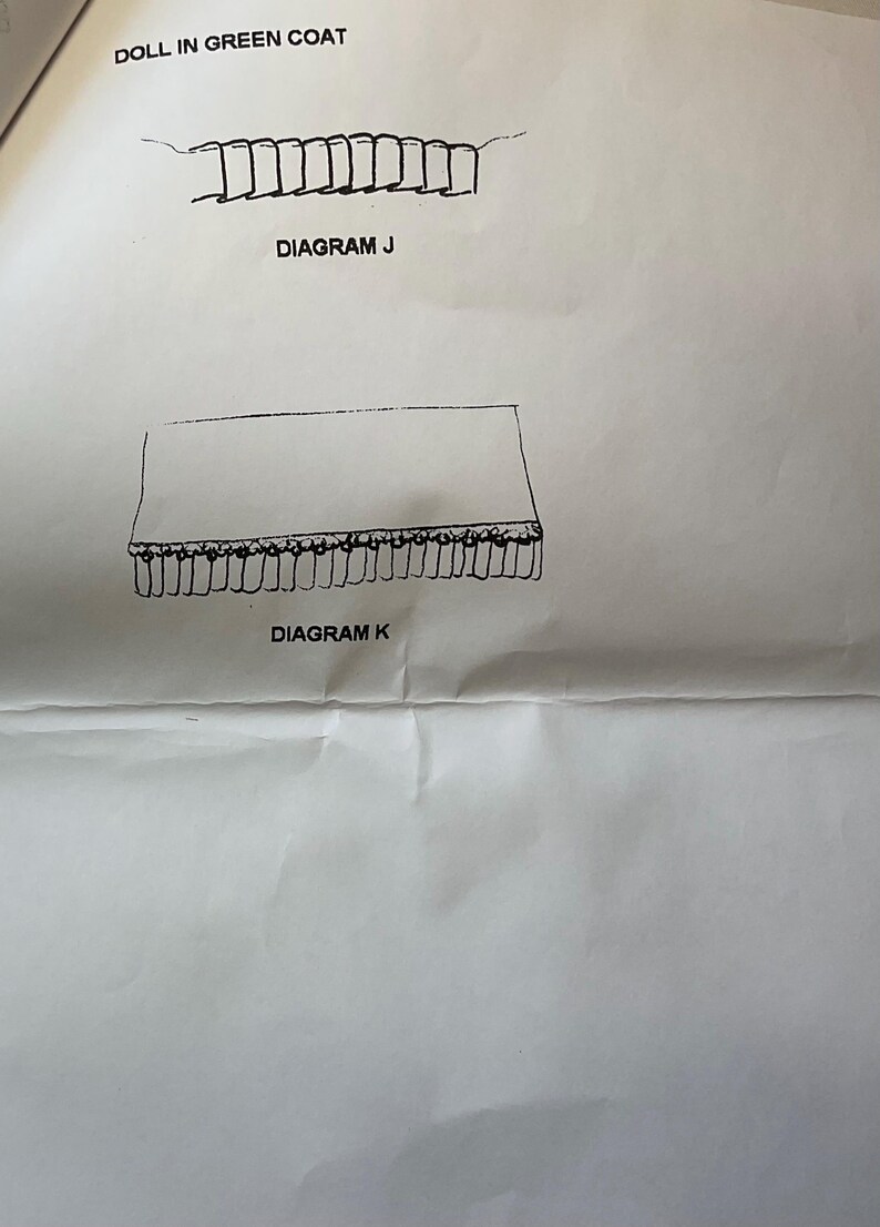 May include: A black and white illustration of two diagrams labeled "Diagram J" and "Diagram K". Diagram J depicts a series of connected rectangles. Diagram K shows a rectangle with a fringe along the bottom edge. The text "DOLL IN GREEN COAT" is at the top.