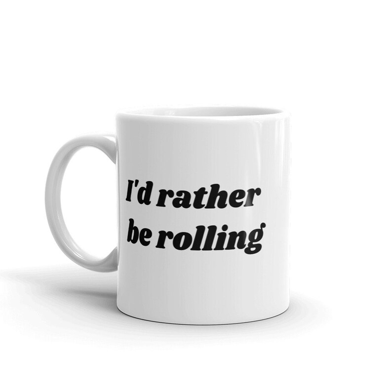 May include: White ceramic mug with black text that reads "I'd rather be rolling".