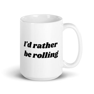 May include: White ceramic coffee mug with black text that reads "I'd rather be rolling".