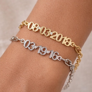 Puede incluir: Dos pulseras personalizadas, una dorada y otra plateada, cada una mostrando una fecha. La pulsera dorada muestra "08-03-2018" con pequeños detalles de diamantes. La pulsera plateada muestra "03-19-16" con detalles similares. Ambas son de estilo cadena.