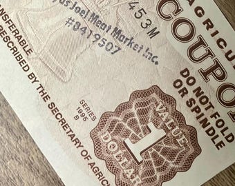 May include: A close-up of a brown and white agricultural coupon. The coupon reads "DOLLAR VALUE 1" and "SERIES 1995 B." The text "Kiryas Joel Meat Market Inc." and "#8419507" are also visible.
