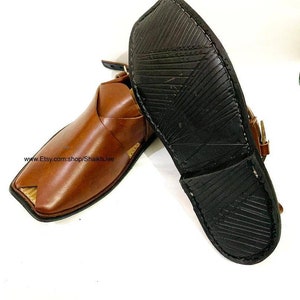 K&ouml;nnte beinhalten: Ein Paar braune Peshawari-Ledersandalen mit quadratischer Zehenpartie und Riemen. Die Sandalen haben eine dunkelbraune Sohle mit strukturiertem Muster. Der Etsy-Shop-Name ist sichtbar.