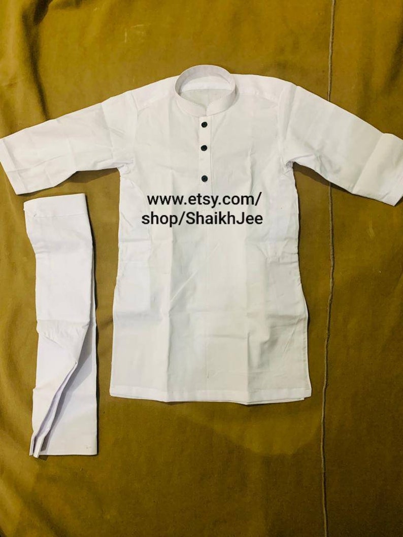 May include: White kurta pajama set. The top has a mandarin collar and three black buttons. The text "www.etsy.com/shop/ShaikhJee" is printed on the image. The set is made of a lightweight fabric.