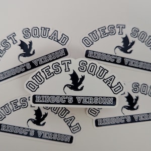 May include: Five white stickers with black text and a black dragon graphic. The text on the stickers reads "Quest Squad Riddoc's Version".