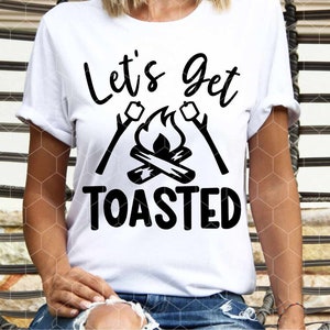 May include: White t-shirt with black text that reads "Let's Get Toasted" with a campfire and marshmallows graphic.