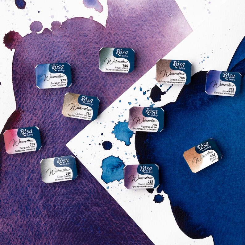 May include: A collection of 10 watercolor paint pans in various colors, including blue, green, purple, and brown. Each pan has a silver label with the brand name "R&oacute;sa" and the color name in both English and Russian.