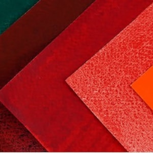 May include: A collection of ten fabric swatches in various colours, including blue, green, red, orange, and brown. The swatches are arranged in a diagonal pattern, with the darkest colours at the top and the lightest colours at the bottom.