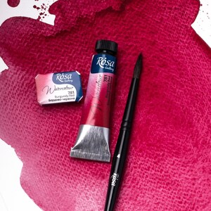 May include: A tube of Rosa Gallery Watercolor paint in Burgundy Red (781) with a small pan of the same color. The paint is on a white surface with a red watercolor wash.