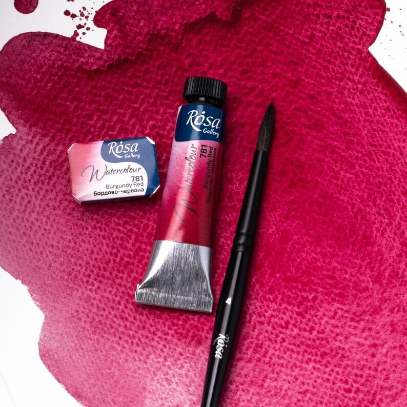 May include: A tube of Rosa Gallery Watercolor paint in Burgundy Red (781) with a small pan of the same color. The paint is on a white surface with a red watercolor wash.