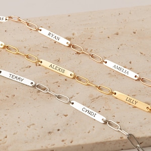 May include: Five gold, silver, and rose gold chain bracelets with personalized nameplates. The nameplates are engraved with the names "Nicholas", "Pamela", "Ryan", "Alexis", "Amelia", "Terry", "Lilly", and "Cyndi".
