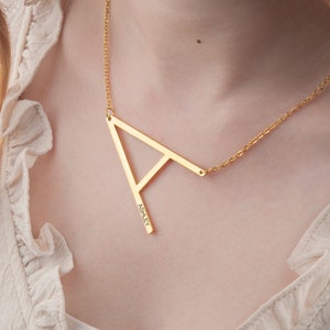 May include: A gold necklace with a large, geometric letter 'A' pendant. The pendant is engraved with the name "Ashley".