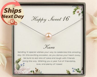 May include: A white gift box with a floral design and a silver necklace with a pink pearl pendant. The box has the text "Happy Sweet 16" and the name "Kara" printed on it. The text "Sending 16 special wishes your way to celebrate this amazing day. On this exciting occasion, as you dance your heart away, be sure to eat lots of cake and laugh with friends along the way. Wishing you a year full of friendship, love, and plenty of roses!" is also printed on the box.
