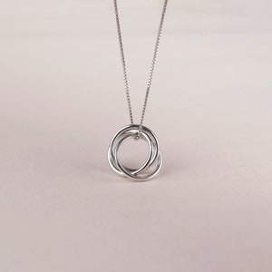 May include: A silver necklace with a pendant featuring three interlocking circles.