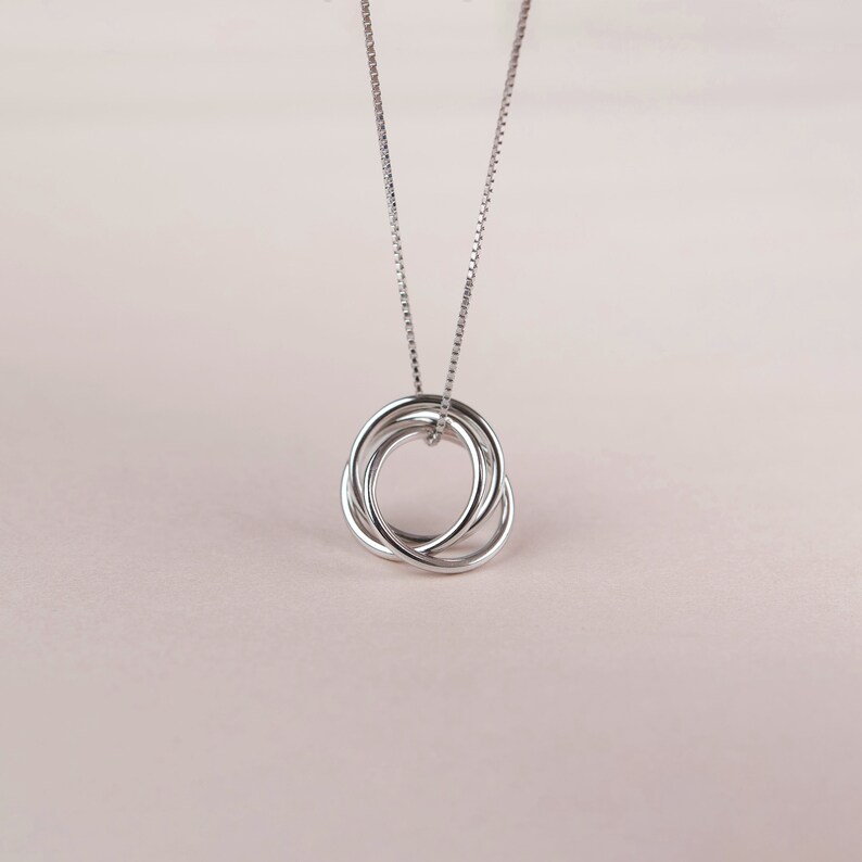 May include: A silver necklace with a pendant featuring three interlocking circles.