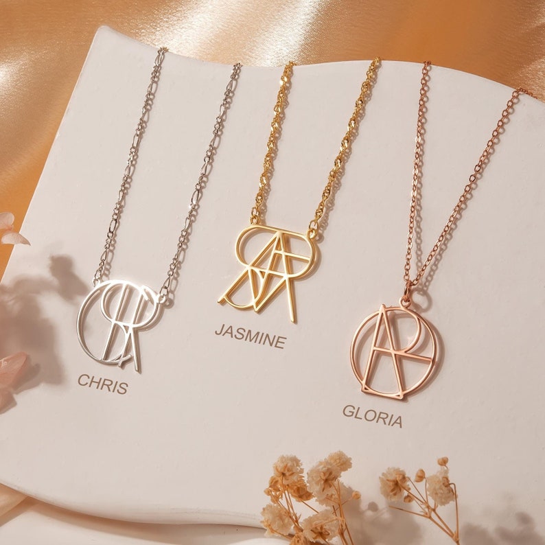 May include: Three gold necklaces with geometric initial pendants. The necklaces are on a white background with the names "Chris", "Jasmine", and "Gloria" printed below each pendant.