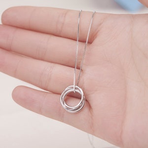 May include: A silver necklace with a pendant made of five interlocking rings.