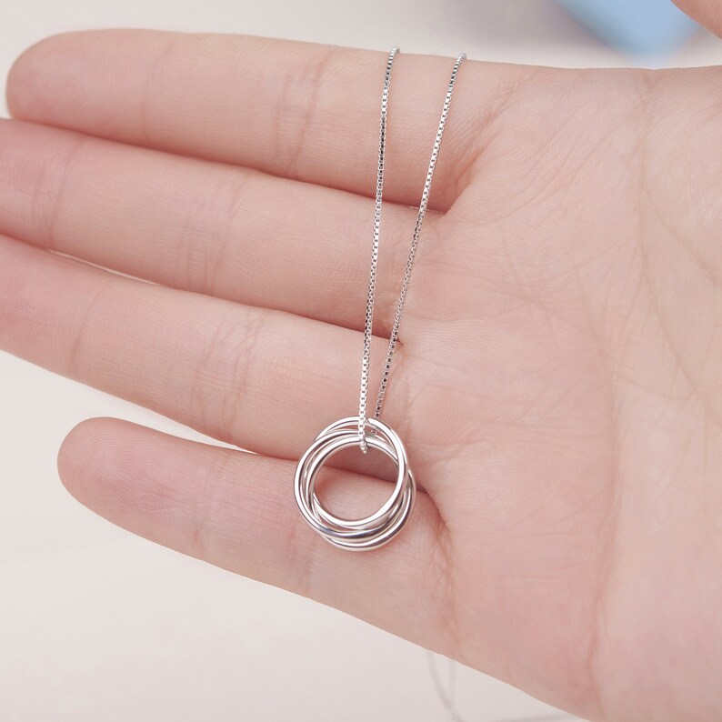 May include: A silver necklace with a pendant made of five interlocking rings.