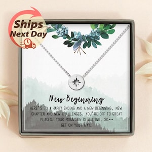 May include: A silver-colored necklace with a compass pendant, presented in a gift box. The box features a watercolor design with the words "New Beginning" and an inspirational message. The image also includes a "Ships Next Day" graphic.
