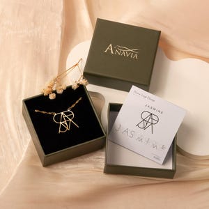 May include: A gold necklace with a custom name design in a green box. The box has the name "Anavia" printed on the top. The necklace is in a smaller box with the name "Jasmine" printed on the top.