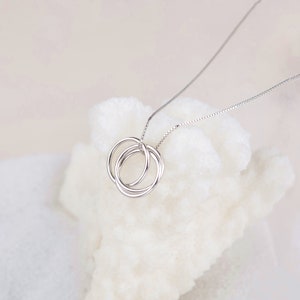 May include: A silver necklace with a pendant featuring three interlocking circles.