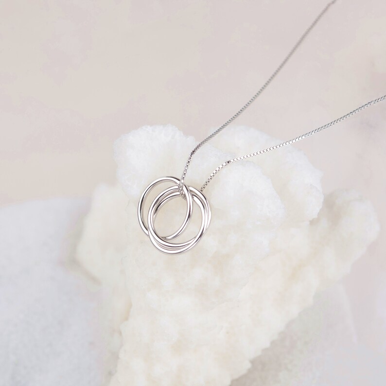 May include: A silver necklace with a pendant featuring three interlocking circles.