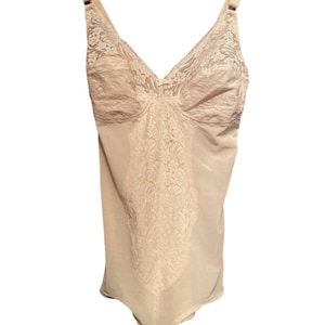 Puede incluir: Un body de encaje beige con tirantes ajustables. El body tiene un escote en V y un diseño liso y sin costuras.