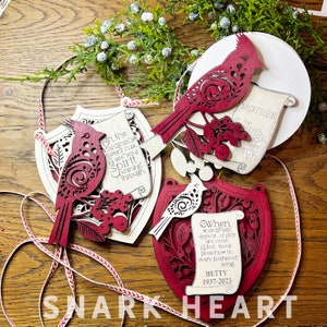 May include: Four wooden ornaments featuring red cardinals with intricate designs and inspirational quotes. The quotes include "When cardinals appear, angels are near", "On the cardinal's vibrant hue, see your spirit shining through", "Mother, on the wings of night, forever sings", and "Betty 1937-2023".