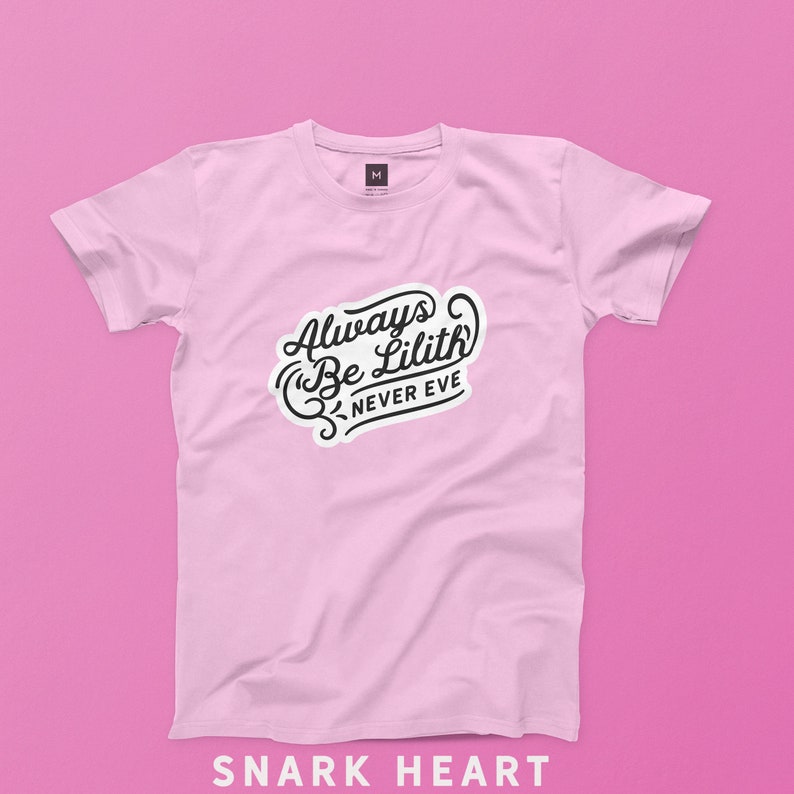 Peut inclure: Un t-shirt rose avec le texte "Always Be Lilith Never Eve" en lettres d'&eacute;criture noire.
