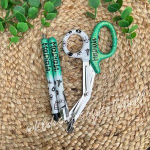 May include: Two green and white glitter pens with the name "Maddiah" on them and a pair of green and white glitter medical shears with the name "Maddiah" on them.