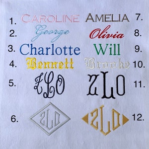 May include: White fabric with embroidered names and monograms in various colors and fonts. Names include Caroline, George, Charlotte, Bennett, Amelia, Olivia, Will, and Brooke. Monograms and geometric designs are also featured.