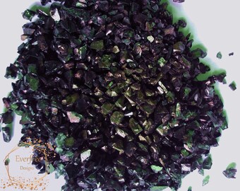 May include: A pile of iridescent black and green glass chips. The chips are small and irregular in shape. They are perfect for use in crafts and home decor.