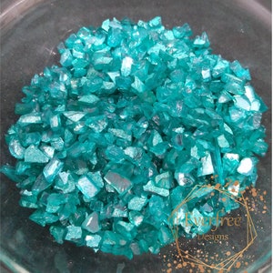 May include: A bowl filled with turquoise iridescent glass pieces. The glass pieces are of various sizes and shapes.