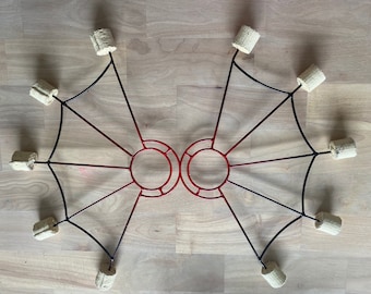 May include: A pair of black and red metal fire poi with eight wick tips. The poi are designed with a circular hoop at the center of each wing.