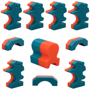 Könnte beinhalten: Satz von zehn bunten Plastik-Puzzleteilen in Teal und Orange. Die Teile sind in Form von Bögen, einer Krone und einer einzigartigen abstrakten Form.