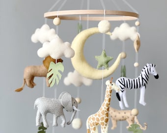 May include: A wooden baby mobile with a yellow crescent moon, a green star, white clouds, a brown giraffe, a gray elephant, a brown lion, a black and white zebra, and green leaves.