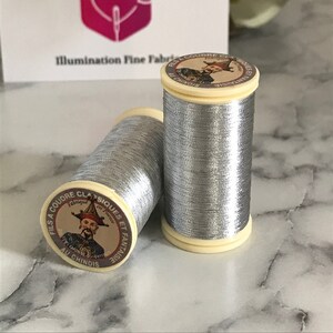 May include: Two spools of silver metallic thread with a label that reads "FILS A COUDRE CLASSIQUES ET FANTAISIE Fabriqué en France AU CHINOIS".