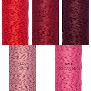 May include: Four spools of thread in various shades of red and pink. The spools are labelled with numbers and colour names, including #473 Mauve and #890 Medium Pink.