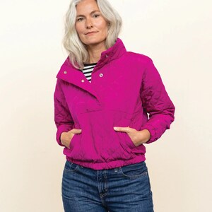 May include: A magenta quilted pullover with a snap closure and a kangaroo pocket. The pattern is called "The Pogonip Pullover" and is from Friday Pattern Co. The pattern is for sizes XS to 7X.