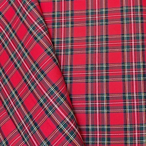 May include: Close-up of two pieces of red plaid fabric. The plaid pattern includes green, white, and yellow lines. The fabric is folded, showing the pattern at different angles. The fabric is likely used for clothing or home decor.