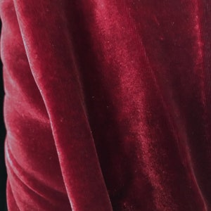 May include: Close-up of a deep red velvet fabric with a soft, plush texture.
