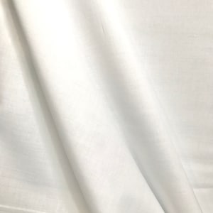 May include: White fabric with a smooth, silky texture. The fabric is folded and draped, creating soft folds and curves.