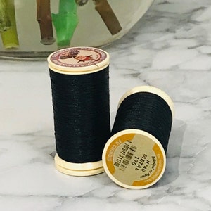 May include: Two spools of black thread with white labels. The labels have the text "METAL 1770 N. 40" and "FIL A COUDRE 1108371116 40 CHINOIS".